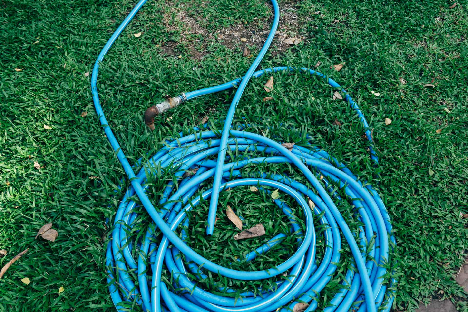 White drinking-water hose coiled beside a camper